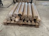 many rolls of fabric sitting on a pallet in a warehouse