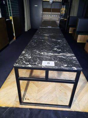 une table en marbre noir avec un piètement en métal, posée à même le sol