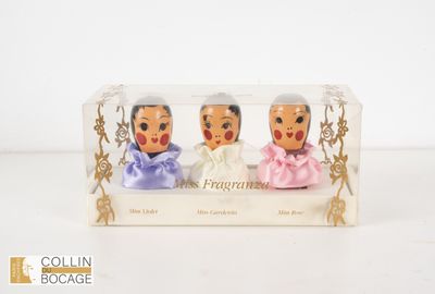 trois figurines dans une boîte transparente posée sur un fond blanc