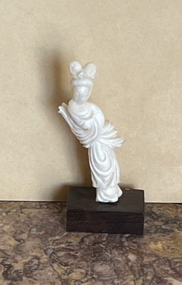 une statue représentant une femme tenant un livre sur une table en marbre
