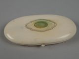 une image représentant un objet ovale blanc avec une pierre verte au centre