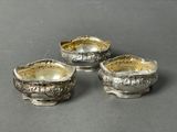 three silverplated dishes on stands on a gray surface
