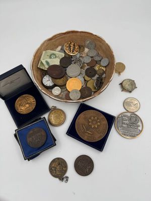 un bol rempli de pièces et une boîte de pièces posés sur une table