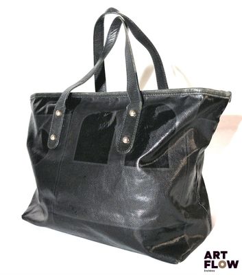 sac fourre-tout en cuir noir sur fond blanc, avec un texte stylisé en flux continu