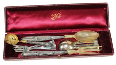 des couverts dans une boîte rouge posée sur un fond blanc, avec une cuillère dorée et un repose-cuillère