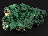 un gros plan d'un morceau de minéral vert sur une surface noire