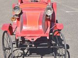 an old red car that is parked in a parking lot