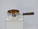 a silver bowl with a wooden handle on a white pedestal