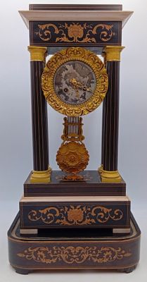 une horloge posée sur un support sur lequel se trouve une autre horloge