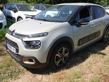 une voiture argentée garée dans un champ, avec d'autres voitures en arrière-plan