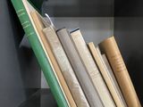 Plusieurs livres sont empilés sur une étagère dans une bibliothèque.
