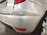 the rear end of a white car with a denting on it