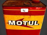 une vieille boîte Motul rouge et jaune sur laquelle est accrochée une étiquette