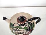 a small tea pot with a handle on a white table