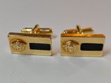 a pair of gold and black cufflinks with lion heads