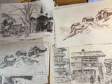 Plusieurs croquis de bâtiments et d'une église sont posés sur une table
