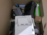 a white printer sitting in a cardboard box next to a pile of electronics
