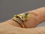 Quelqu'un tient une bague en or sertie d'une pierre verte.