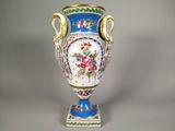 un vase bleu orné de fleurs, posé sur un socle