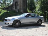 a silver mustang parked in front of a church