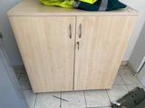a wooden cabinet with two doors and a bag on top of it