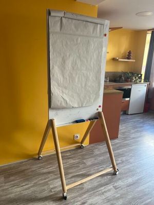 un tableau blanc posé sur un support en bois dans une pièce jaune