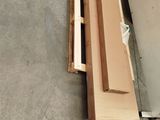 a piece of wood sitting on the floor next to a refrigerator