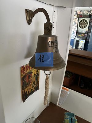 une cloche accrochée au mur, sur laquelle est accrochée une étiquette bleue