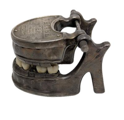 a metal toothbrush holder with a tooth on it