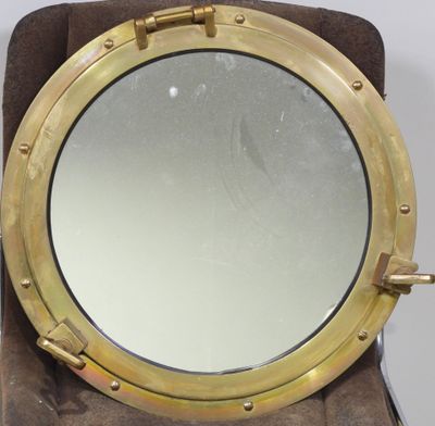 miroir en forme de hublot en laiton, présenté sur un socle en velours marron