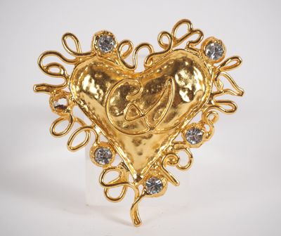 a close up of a gold heart shaped brooch with diamonds