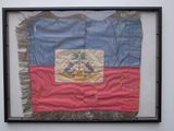 an old flag hanging on a wall in a black frame