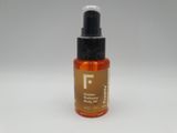 a close up of a bottle of body oil on a white surface