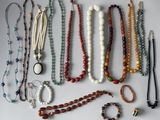 many different necklaces and bracelets laid out on a table