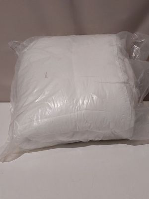 un oreiller blanc posé sur une table blanche près d'un mur blanc
