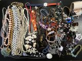 many different necklaces and bracelets laid out on a table
