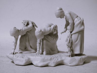 une figurine représentant une femme aidant un homme à mettre quelque chose dans l'eau
