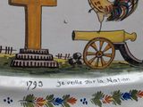 a plate with a rooster and a cannon on it
