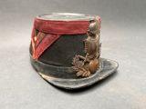 un petit chapeau orné d'un ruban rouge et d'un oiseau