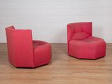 une paire de chaises pivotantes rouges dans une pièce blanche avec un parquet