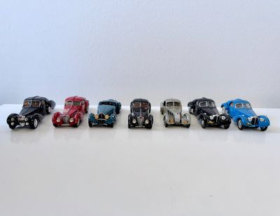 six petites voitures sont alignées en rang sur une surface blanche