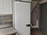 a white refrigerator in the corner of a room with tile flooring