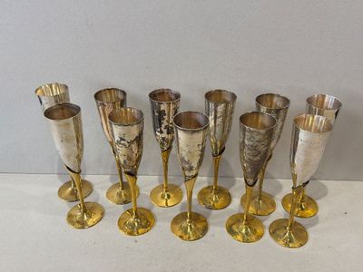 six verres à vin en argent et en or alignés sur une surface blanche