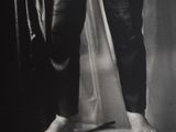 an old black and white photo of a person standing on top of a suitcase