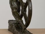 statue of a man holding a wheel on a wooden table