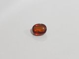 an oval shaped orange sapphire stone on a white surface