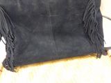 leather purse with fringes on top of it sitting on a table