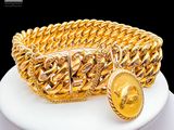 a gold bracelet with a coin on a white plate