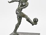 statue représentant un homme en train de frapper un ballon de football, posée sur un socle en marbre