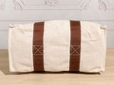 a white and brown canvas bag sitting on top of a wooden table